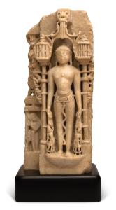 Standing erect within a columnar niche, wearing a belt and diaphanous dhoti, an arch above