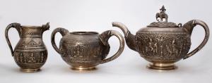 Comprising of a teapot, creamer and sugar bowl, each piece with repoussé decoration depict
