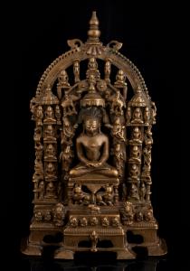 The central tirthankara seated on a lion throne under a parasol, flanked by apsaras and at