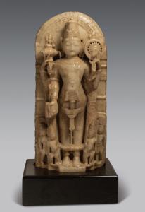 The four-armed deity standing under an engraved arch holding gada, chakra and mala in the 