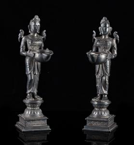 Each standing on double lotus on square plinth, holding an oil burner in front, a parrot p