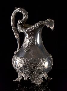 Of baluster form raised upon four cast vine bracket feet, the reeded loop handle capped wi