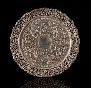 Of circular form, profusely decorated with chased and repousse hunting scenes amidst dense